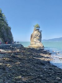 Rock formation on beach against clear blue sky