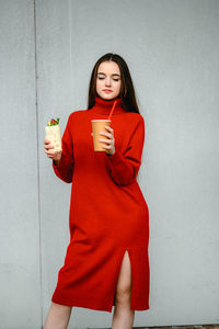 A girl in a red dress holds a shawarma and a glass of coffee in her hands. sausages 