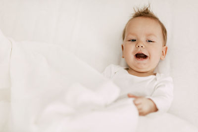 Portrait of cute baby girl on bed at home