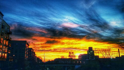 Silhouette of buildings against cloudy sky at sunset