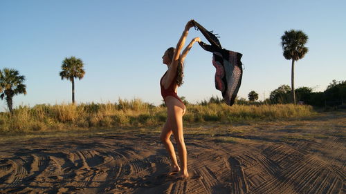 Woman standing on tree against clear sky