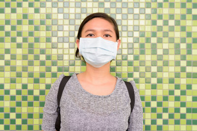 Portrait of woman standing against wall
