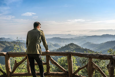 Rear view of man looking at mountains against sky