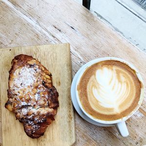 High angle view of coffee cup with roasted ham on table