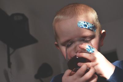 Close-up of boy drinking red wine at home