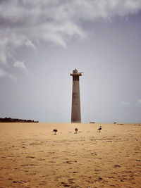 Lighthouse on beach against sky