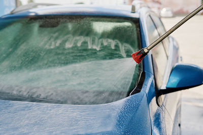 Cleaning car with high pressure water at car wash station