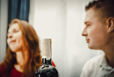 Close-up of wine bottle with friends in background