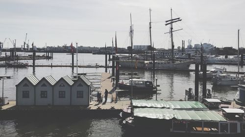 Sailboats moored at harbor against sky