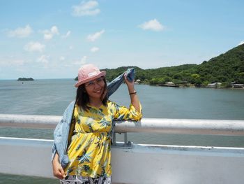 Woman standing by railing against sea