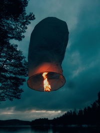 Low angle view of lit candle against sky at dusk
