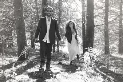 Full length of man and woman walking in forest