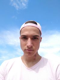 Portrait of young man wearing cap against sky