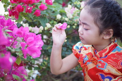 Girl holding pink flower by plants