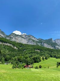 Scenic view of field and mountains against blue sky