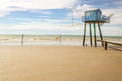 Lifeguard hut on beach against sky