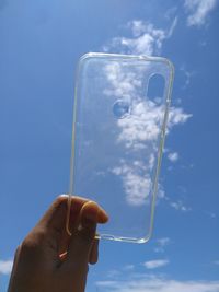 Person holding phone case against sky