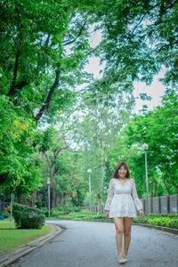 Portrait of woman standing on road against trees