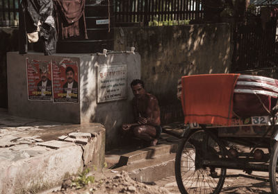 Portrait of man sitting against built structure