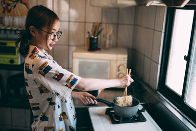 Side view of woman preparing food in kitchen
