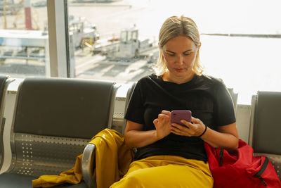 Young woman using mobile phone while sitting in gym