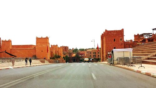 Road leading towards buildings against sky