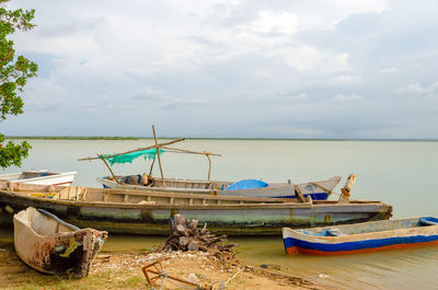 Boats moored at riverbank against sky