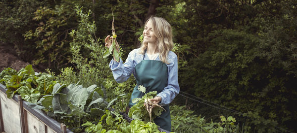 Woman holding umbrella standing by plants