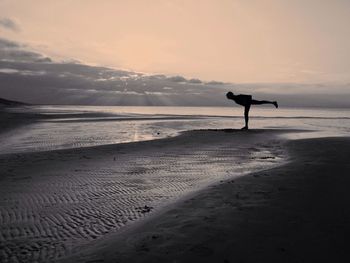 Silhouette man exercising on beach