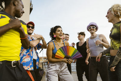 Happy non-binary person having fun while dancing amidst friends in city