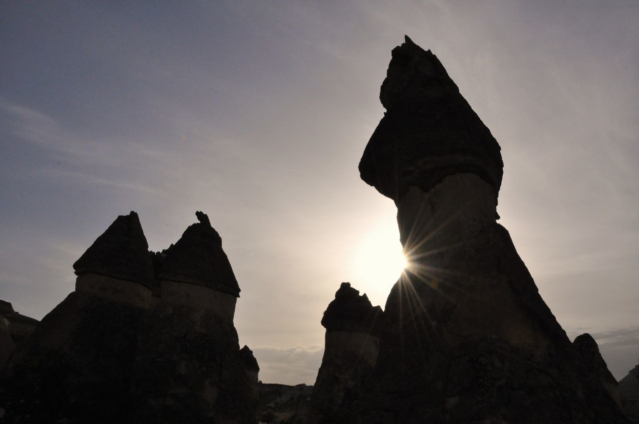 sky, architecture, sunset, history, built structure, low angle view, rock, the past, nature, solid, no people, rock - object, travel destinations, sun, rock formation, religion, sculpture, tranquility, beauty in nature, building exterior, outdoors, lens flare