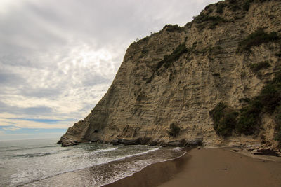 Scenic view of cliff by sea against sky