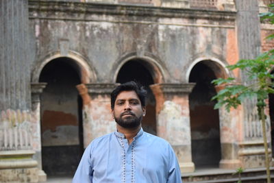 Portrait of bearded man standing against historical building