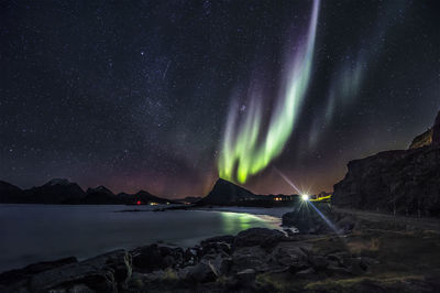 Scenic view of sea and mountains against sky at night