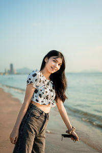 Young woman standing at beach against clear sky