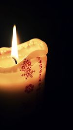 Close-up of illuminated candle against black background