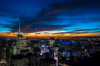 Aerial view of illuminated cityscape against cloudy sky at night