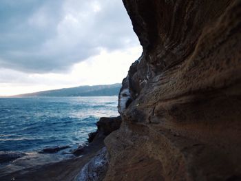 Rock formation by sea against sky