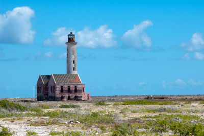 Lighthouse on field against sky