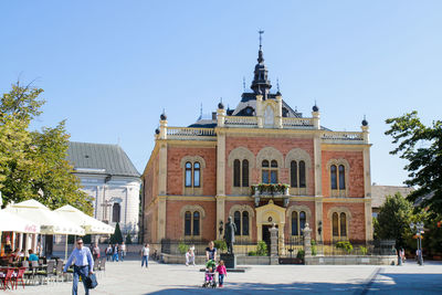 Group of people in front of building against clear blue sky