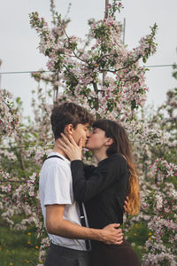 Young strong love between two wonderful people walking under apple trees. kiss of pure love.