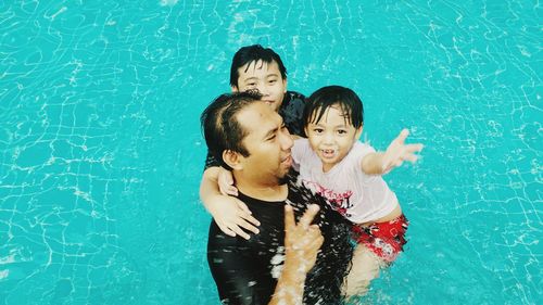 Portrait of father with daughter and son in swimming pool