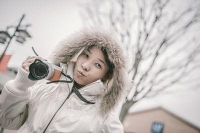 Portrait of woman puckering while holding camera during winter