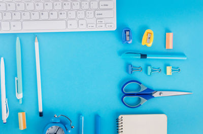 Directly above shot of office supplies over blue background