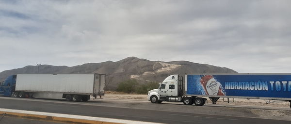 Cars on road against cloudy sky