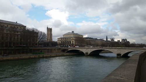 Arch bridge over river against cloudy sky