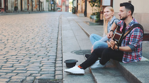 Young couple sitting on street in city