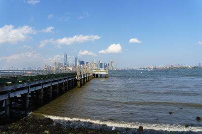 View of city at waterfront against cloudy sky