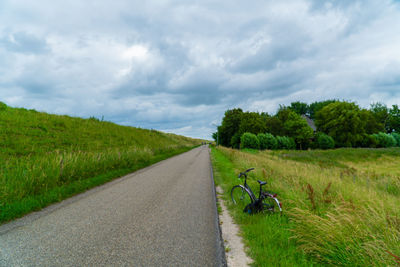 Road amidst field against sky