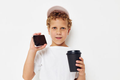 Portrait of young woman using mobile phone against white background